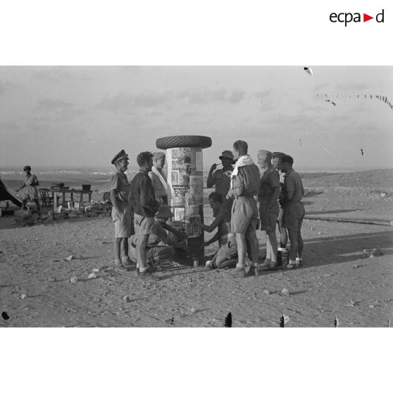 Une colonne de fortune est utilisée par des soldats allemands pour y coller des photographies tirées de magazines.