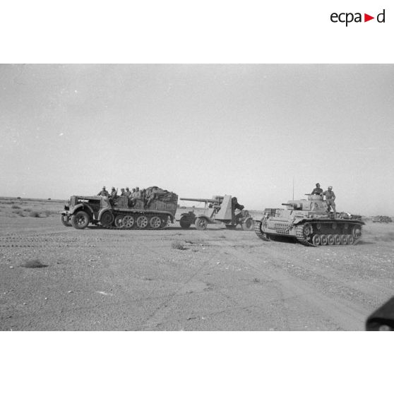 Un tracteur d'artillerie Sd/kfz.7 et une pièce d'artillerie 8,8 cm FlaK devant un blindé Panzer III.