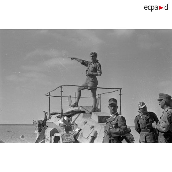 Le chef d'une unité de reconnaissance (Spähtruppführer), l'adjudant (Feldwebel) Apsel observe aux jumelles sur le toit d'un Sd.kfz.223 (immatriculé WH 642 265).