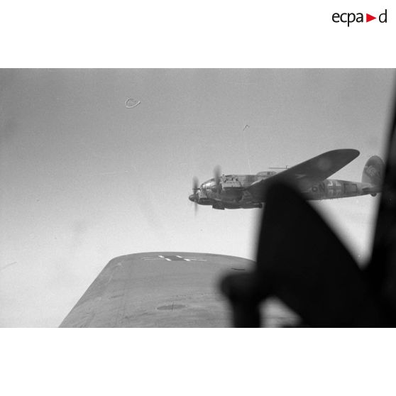 Dans un Heinkel He-111 lors d'une mission de bombardement au sein du Kampfgruppe 100 (KG 100).