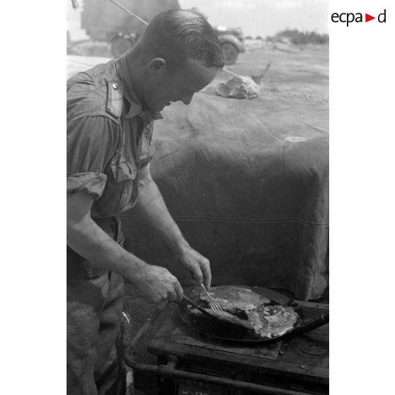 Une cuisinière en fonte réchauffe le repas d'un sous-officier.