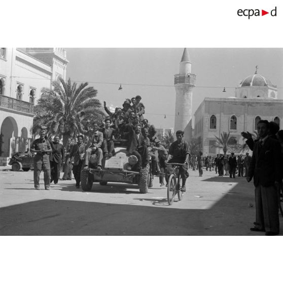 Des civils italiens sont juchés sur un blindé SdKfz-222 qui traverse Benghazi.