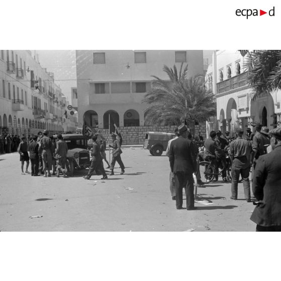 A Benghazi, une voiture italienne arbore le drapeau allemand auquel un officier italien ajoute le drapeau italien.