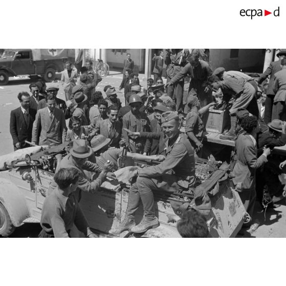 A Benghazi, une voiture Kübelwagen de l'état-major de l'Aufkl-Abtelung-3, les soldats allemands sont entourés de civils et de militaires italiens.