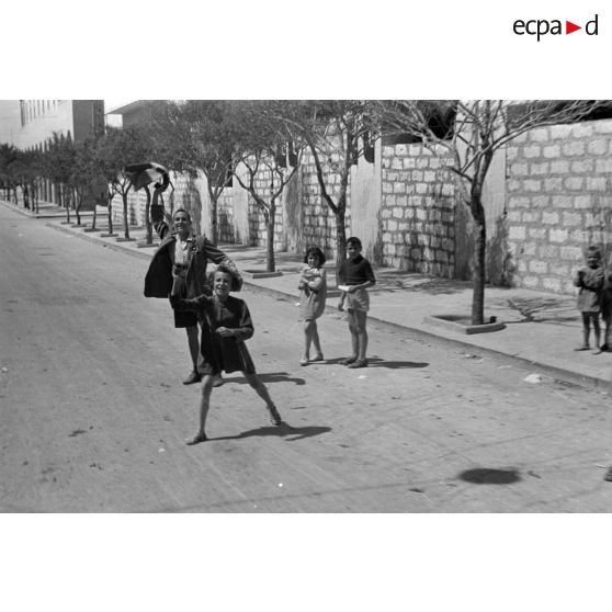 A Benghazi, une vue subjective de jeunes Italiens acclamant les troupes allemandes qui passent en véhicules.