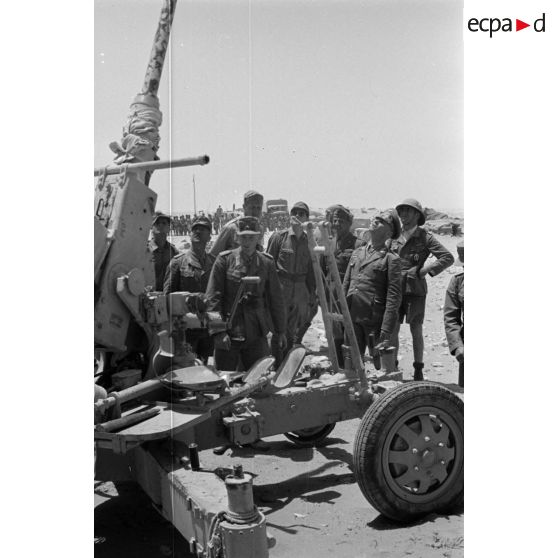 Le général Erwin Rommel accompagné d'officiers inspecte un canon de DCA anglais Bofors de 40 mm.