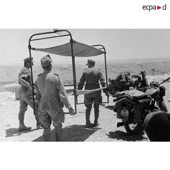 Trois soldats transportent un lit superposé près de deux motos NSU 601 OSL de 600 cc.