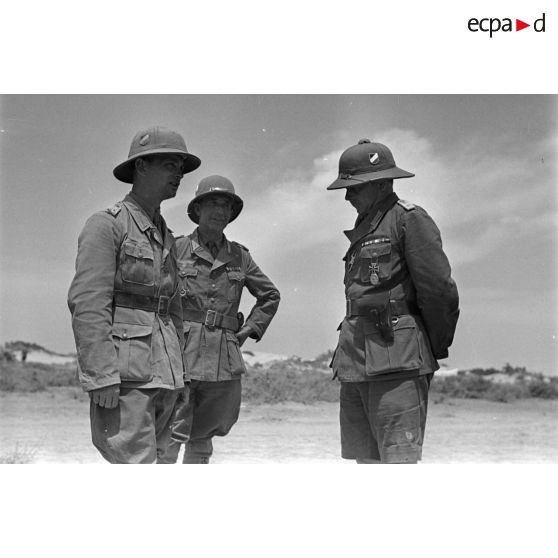 Trois officiers allemands discutent, dont un capitaine (Hauptmann) et un lieutenant (Oberleutnant).