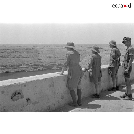 Trois artistes regardent la mer.