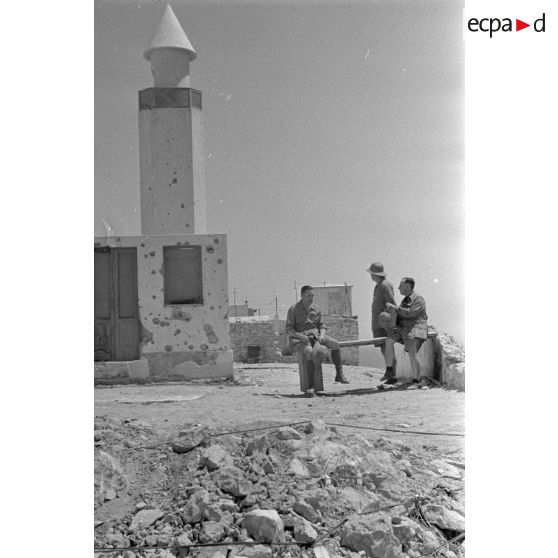 Trois artistes se promènent dans les rues de Bardia. Une mosquée en arrière-plan.