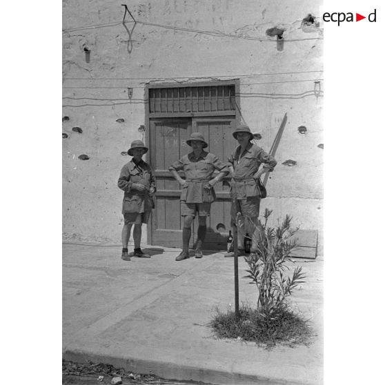 A Bardia, trois artistes posent devant l'entrée d'un bâtiment.