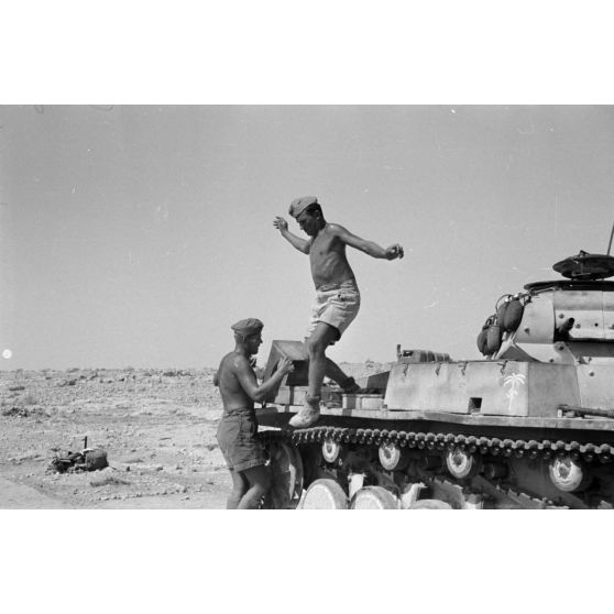 Un homme d'équipage saute de son Panzer II (Pz-II Ausf-C) tandis qu'un autre décharge une caisse.