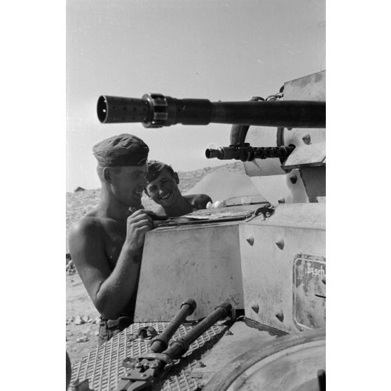 Un homme d'équipage casse des oeufs sur la plaque d'un casier extérieur du Panzer II et les fait cuire.