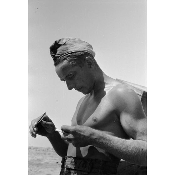 Un soldat allume sa cigarette à l'aide d'une loupe.