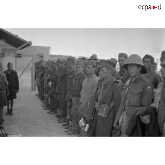 Un groupe de nouveaux prisonniers britanniques, au premier plan un soldat porte l'insigne de la 1re division d'infanterie sud-africaine.