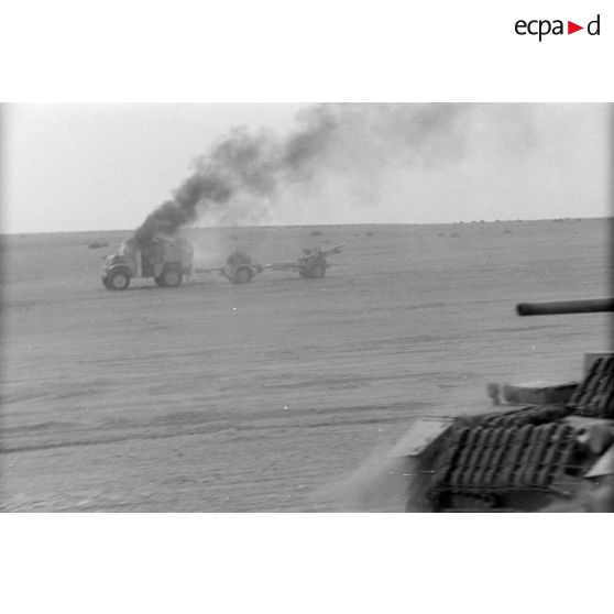Un Panzer III (Pz-III) passe près d'un camion Quad et d'un canon QF de 25 et son avant-train.