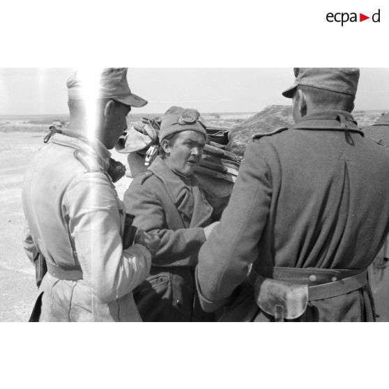 Des soldats allemands et un Italien discutent près d'un véhicule.