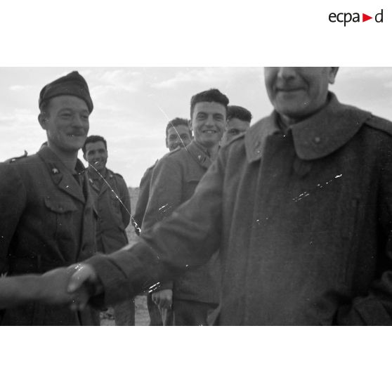 Un général de division italien est reçu par des officiers et des soldats.