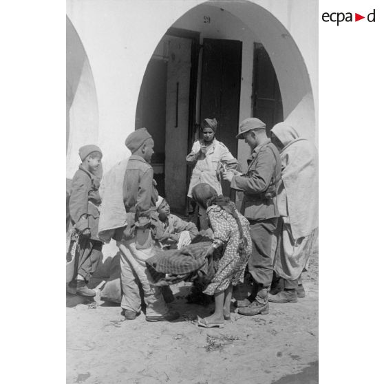 Un soldat allemand, appartenant sans doute à une PK, fait des achats chez des civils libyens.