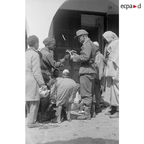 Un soldat allemand, appartenant sans doute à une PK, fait des achats chez des civils libyens.