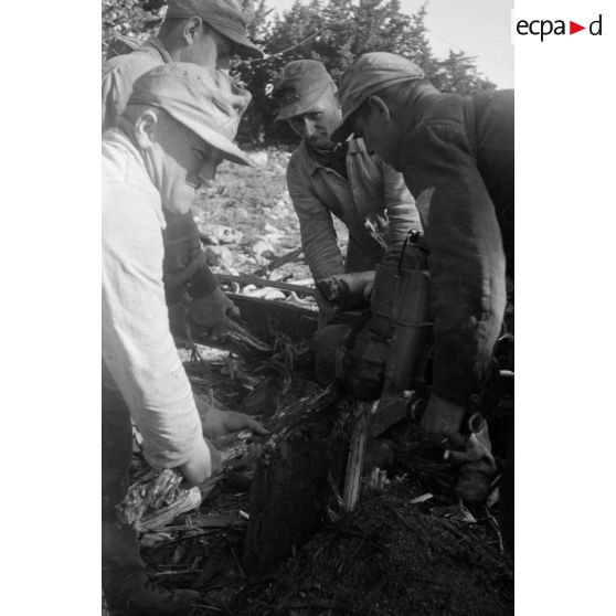 Des soldats coupent du bois avec une scie thermique.