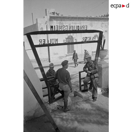 Des soldats discutent sous le porche du foyer où est inscrit : Erholungsheim Panzer Rgt Mueller.