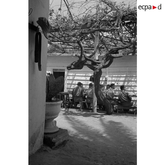 Des soldats discutent, après le repas, près d'une table située à l'extérieur du bâtiment.