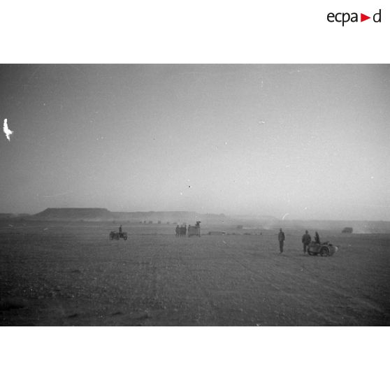 Des motocyclistes et une voiture Kfz-15 sont arrêtés, les soldats observent des véhicules qui progressent.