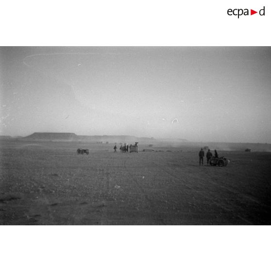 Des motocyclistes et une voiture Kfz-15 sont arrêtés, les soldats observent des véhicules qui progressent.