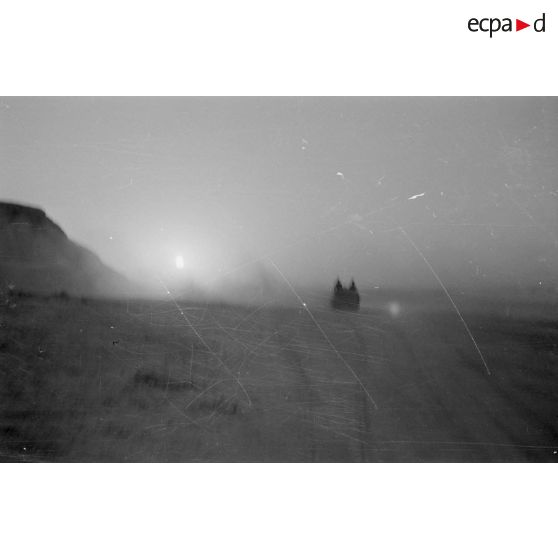 Des véhicules roulent dans le désert en direction d'un secteur de collines.