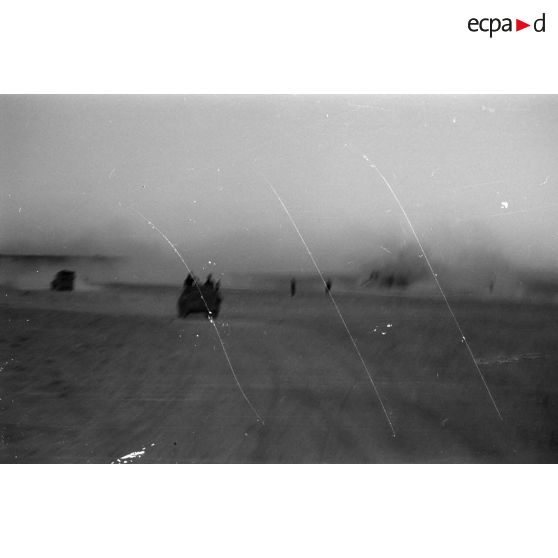 Des véhicules roulent dans le désert en direction d'un secteur de collines.