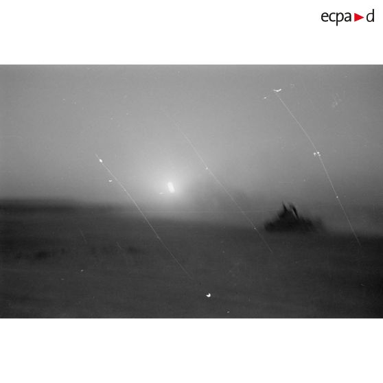 Des véhicules roulent dans le désert en direction d'un secteur de collines.