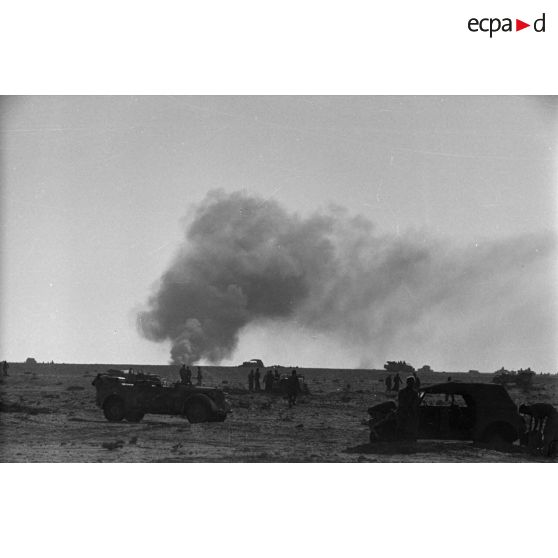 Des véhicules dont des voitures Kübelwagen et Kfz-15 sont entourés de soldats.