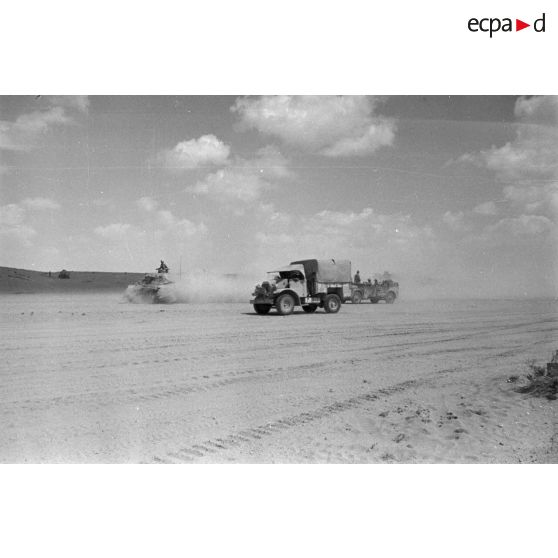 Un camion Ford 3T d'origine britannique roule en compagnie d'une voiture Kfz-15 et d'un char Pz-III.