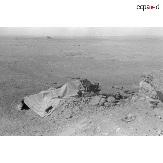 Un canon sFH-18 de 15 cm est installé dans une alvéole et camouflé à l'aide d'une bâche.