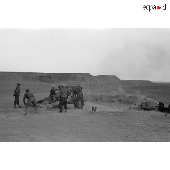 Une batterie d'artillerie en position ouvre le feu, équipée de canons lFH-18 de 10,5 cm et Ordnance QF 25. pounder d'origine britannique.