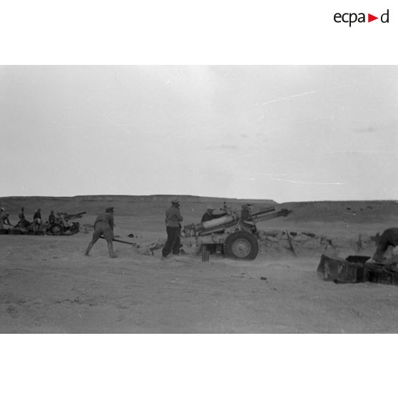 Une batterie d'artillerie en position ouvre le feu, équipée de canons lFH-18 de 10,5 cm et Ordnance QF 25. pounder d'origine britannique.