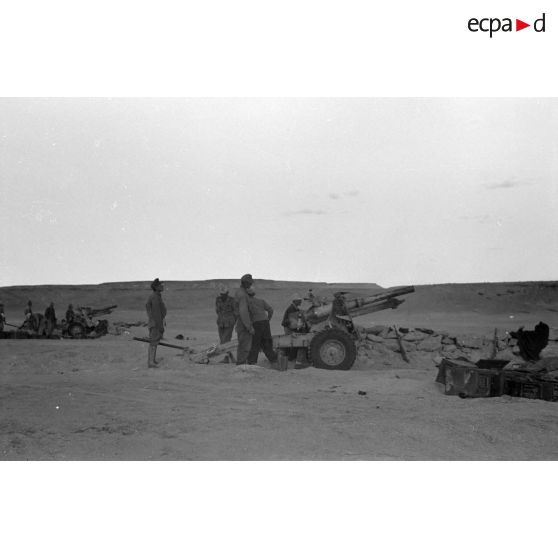 Une batterie d'artillerie en position ouvre le feu, équipée de canons lFH-18 de 10,5 cm et Ordnance QF 25. pounder d'origine britannique.