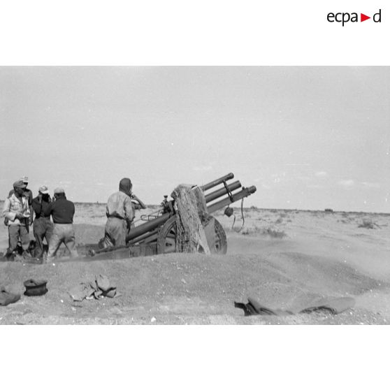 Une batterie d'artillerie en position ouvre le feu, équipée de canons lFH-18 de 10,5 cm et Ordnance QF 25. pounder d'origine britannique.