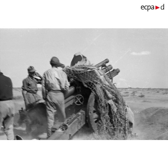 Une batterie d'artillerie en position ouvre le feu, équipée de canons lFH-18 de 10,5 cm et Ordnance QF 25 pounder.