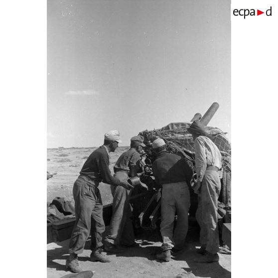 Une batterie d'artillerie en position ouvre le feu, équipée de canons lFH-18 de 10,5 cm et Ordnance QF 25. pounder d'origine britannique.