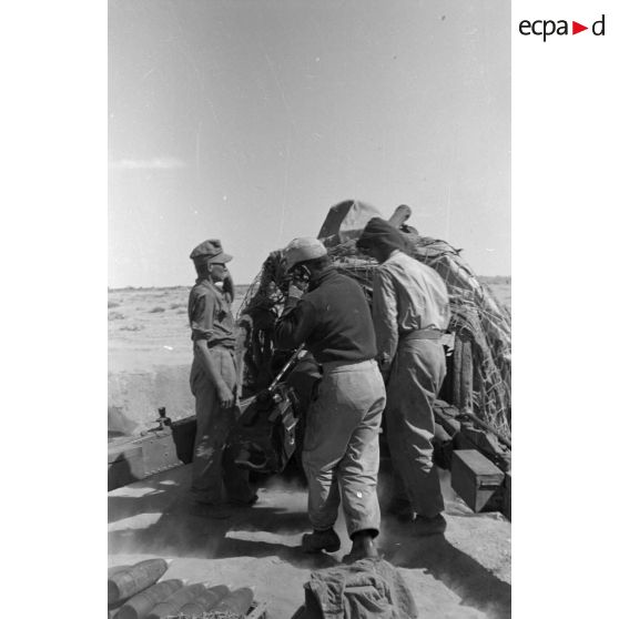 Une batterie d'artillerie en position ouvre le feu, équipée de canons lFH-18 de 10,5 cm et Ordnance QF 25. pounder d'origine britannique.