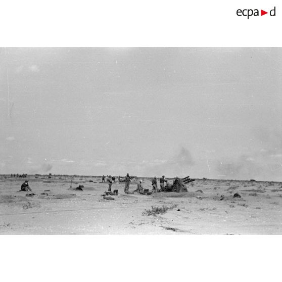 Une batterie d'artillerie en position ouvre le feu, équipée de canons lFH-18 de 10,5 cm et Ordnance QF 25. pounder d'origine britannique.