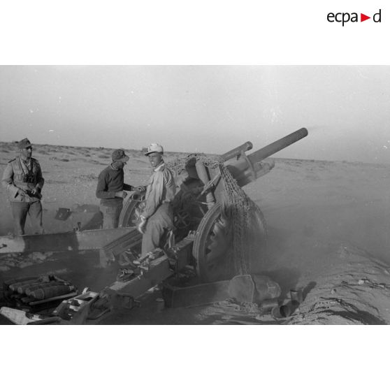 Une batterie d'artillerie en position ouvre le feu, équipée de canons lFH-18 de 10,5 cm et Ordnance QF 25 pounder.