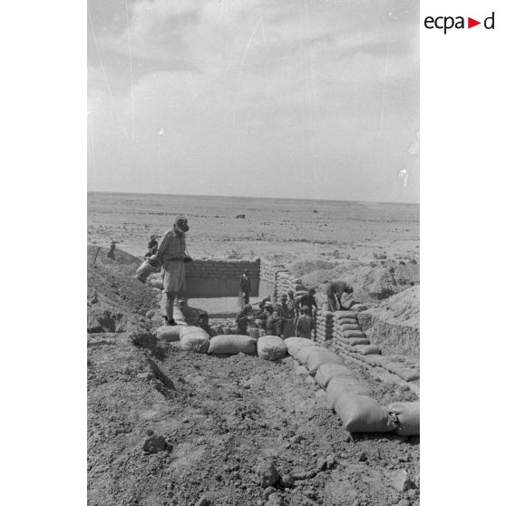 Construction d'un casernement avec des sacs de sable et une toile de tente.