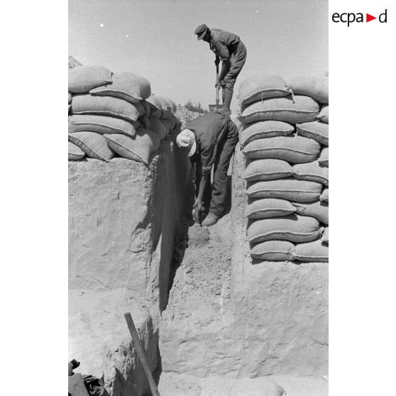 Construction d'un casernement avec des sacs de sable et une toile de tente.