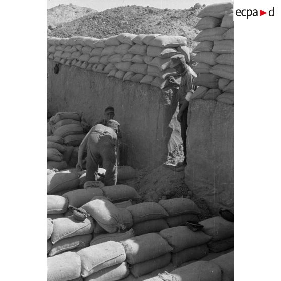 Construction d'un casernement avec des sacs de sable et une toile de tente.