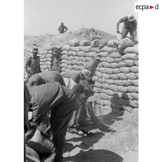 Construction d'un casernement avec des sacs de sable et une toile de tente.