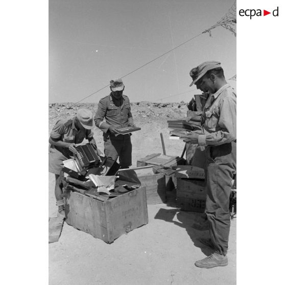 Ouverture de caisses contenant des boîtes et un accordéon sous l'oeil du capitaine (Hauptmann) Reissmann.