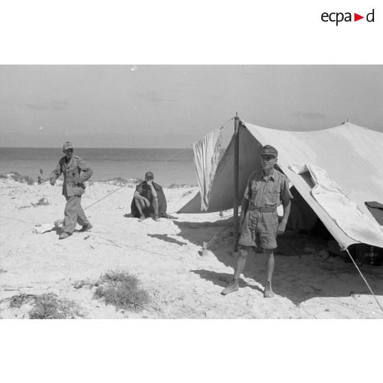 Trois officiers allemands devant une tente plantée sur une plage.